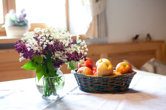 Liebevolle Tischdekoration Blumen und Äpfel auf dem Esstisch im Ferienhaus Katharina